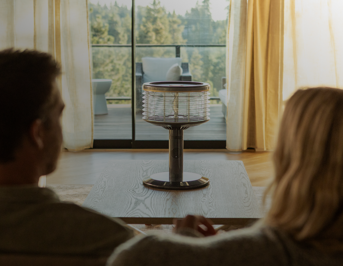 Pareja en el sofá de la sala con el ventilador Orbi360 sobre la mesa, frente a la ventana
